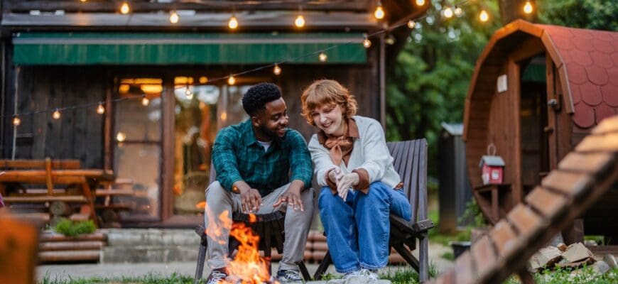 A,Multiracial,Couple,Relaxes,By,A,Warm,Campfire,In,A